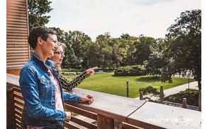 Zwei Frauen stehen auf der Terrasse des Gradierwerks und schauen auf den Kurpark. Die eine Frau zeigt mit dem Finger auf etwas und erzählt der anderen Frau etwas.