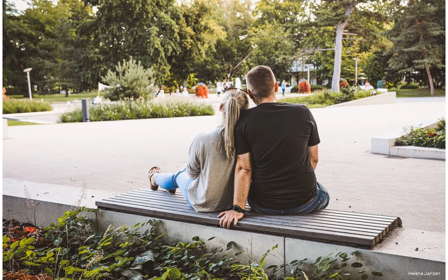 Entspannen im Kurpark Bad Sassendorf Ein junges Pärchen sitzt auf einer Bank im Kurpark. Drumherum sind schöne Blumenbeete angelegt. Leute spazieren im Kurpark.