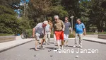 Eine Gruppe Boulespieler (4 Männer und 3 Frauen) auf dem Boulefeld im Kurpark, stehen um ihre geworfenen Boulekugeln herum und erörtern die Ergebnisse.