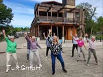 Eine Gruppe unterschiedlicher Menschen tanzt im Kurpark Bad Sassendorf. Alle haben Spaß dabei und lachen.